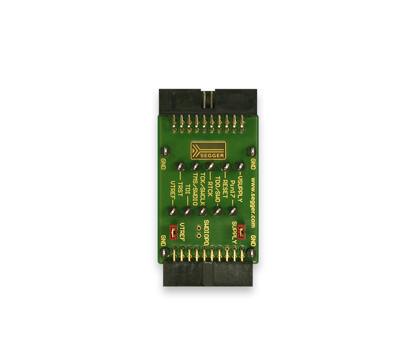 Measurement+Patch Adapter A green electronic circuit board with multiple pin connectors is displayed. The board features labels such as "GND," "U-SUPPLY," and "I/O." The SEgger logo is visible at the center, indicating it is a device component, possibly for programming or debugging electronics.