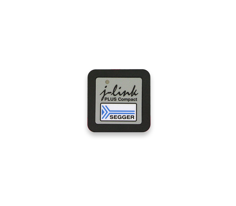 Image description: A square device labeled "j-link PLUS Compact" with a logo that reads "SEGGER." The device has a gray and black color scheme with a small icon featuring an arrow design. The background is plain white, emphasizing the device's features.